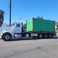 Truck with a green shipping container on a city street