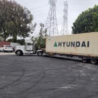 Truck transporting a Hyundai container in a parking lot