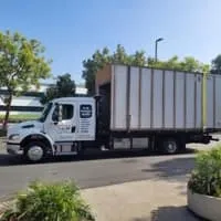 Truck carrying a large container near a building