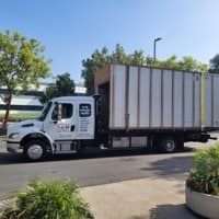 Truck carrying a large container near a building