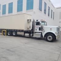 Truck with a beige container parked near a building